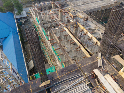 Aerial view of a construction site featuring scaffolding, steel reinforcement bars, and wooden formwork in Indonesia.