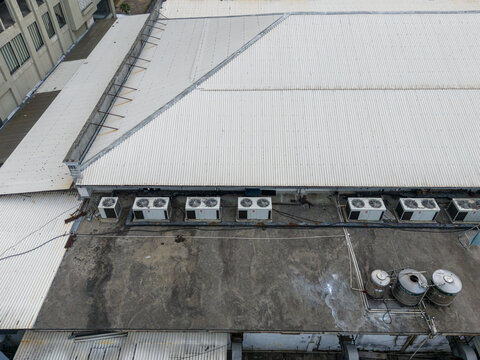 Aerial view of a flat industrial roof featuring multiple HVAC units, corrugated metal panels, and metal water tanks in Indonesia.