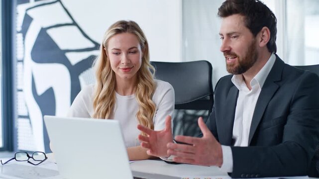 Caucasian business man emotional talk presenting laptop software to woman listening attentive two agents partnership at table businessman happy talking to businesswoman showing computer app at office