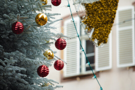 Christmas in Strasbourg, Alsace, France. Red and golden Christmas baubles hanging on a frosted fir tree.
