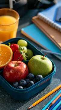 Elegant flat lay of a healthy lunchbox, fresh fruits, juice, notebooks, pencils and backpack accessories, first day of school celebration, ultra realistic, hyper detailed, with