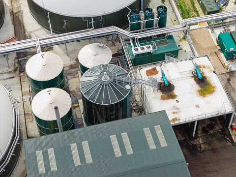 Aerial view of a biogas plant with large industrial storage tanks, metal piping, and processing facilities in the United Kingdom.