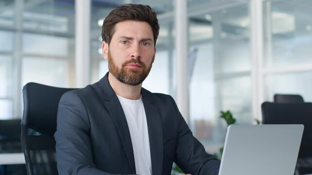 Serious Caucasian middle-aged business man typing laptop looking at camera confident businessman working with computer corporate interface software online work job task mature male worker in office