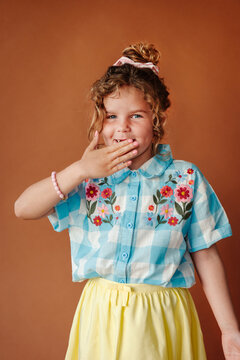 Shy, adorable girl covering her gappy smile