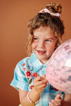 Blond curly hair girl with blue eyes with balloon studio portrait