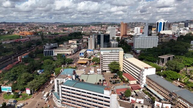 Aerial view of the urban landscape of Kampala featuring high-rise buildings, busy streets, and lush greenery under a cloudy sky in Kampala, Central Region, Uganda.