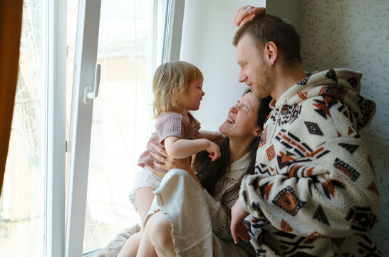 Happy family laughing together on a windowsill at home