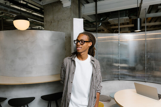 Black entrepreneur with dreadlocks and glasses posing in a workspace.