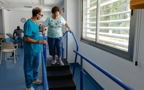 Physiotherapist assisting senior woman walking down stairs