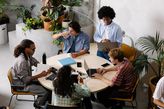 Aerial view of creatives working collaboratively at a shared desk.
