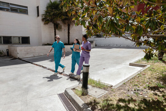 Diverse medical team walking and discussing outdoors