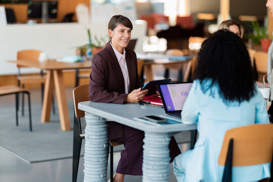 Smiling Businesswoman Leading Informal Office Meeting With Colleagues