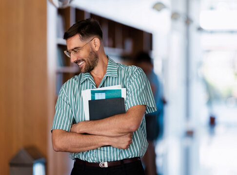 Smiling Man Holding Documents in Office Corridor