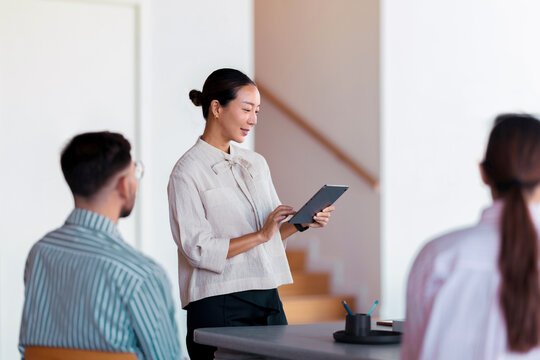 Woman Presenting With Tablet During Business Meeting