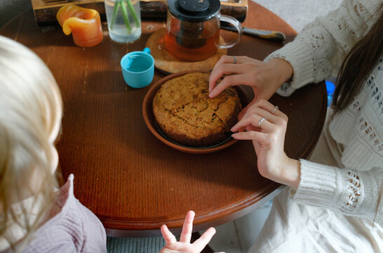 Mother slicing a homemade cake at the kitchen table