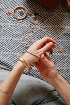 Woman trying on gold bracelets and jewelry at home