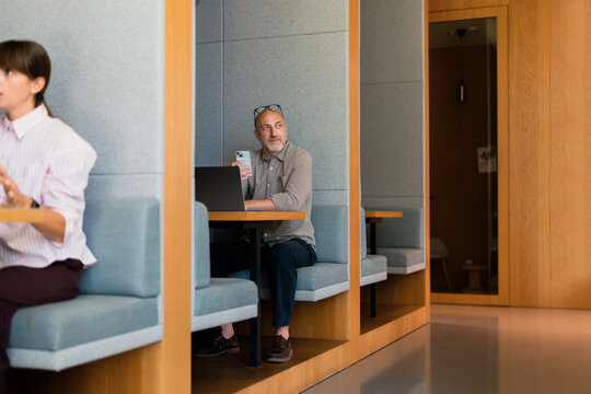 Man Working With Laptop And Phone In Coworking Booth