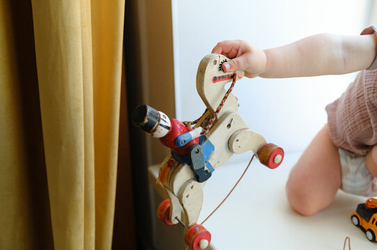 Close-up of a toddler playing with a vintage wooden toy horse