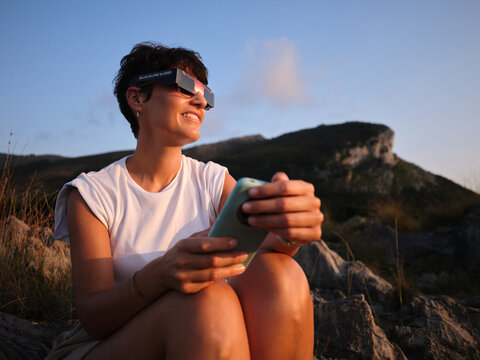 Woman watching solar eclipse wearing protective glasses outdoors