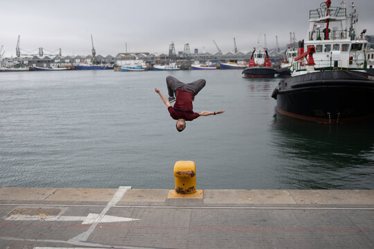 man doing a backflip by the sea harbor 