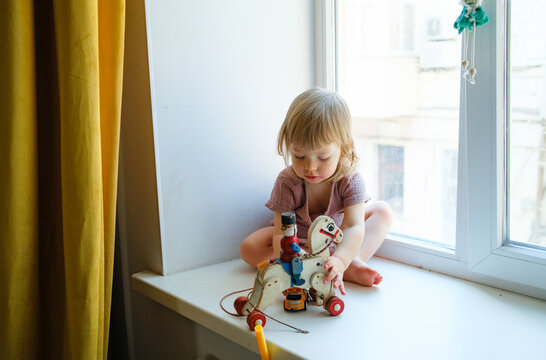 Toddler playing with toys on a wide windowsill
