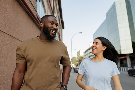 Diverse couple walking street laughing together