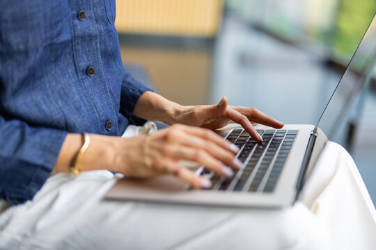 Person Typing on Laptop While Sitting Indoors