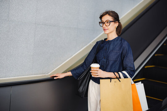 Woman With Shopping Bags Riding Escalator at Shopping Center