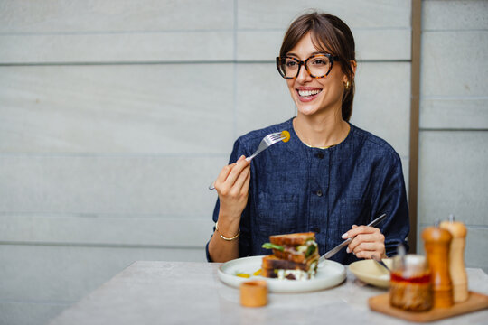 Woman Enjoying Meal at a Cafe With a Smile on Her Face