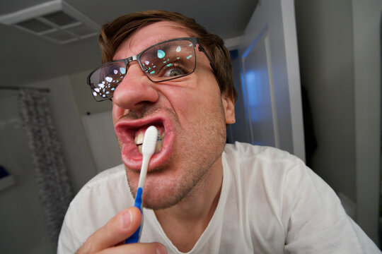 Funny Close Up Portrait of Man Brushing Front Teeth at Home