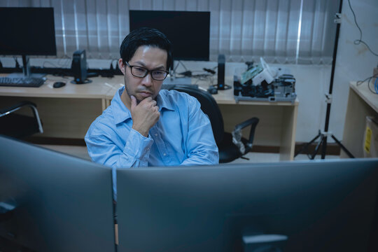 Computer programmer analyzes code across multiple screens while developing and testing software, representing coding, problem solving, productivity, and modern IT work.
