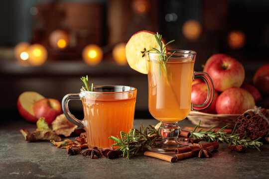 Hot cider with fresh apples, cinnamon, rosemary, and star anise on a kitchen table.
