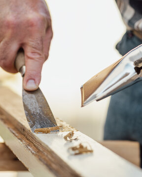 Carpenter using heat gun and wood scraper removes paint from old wooden window. Construction industry, carpentry. Restoration. 
