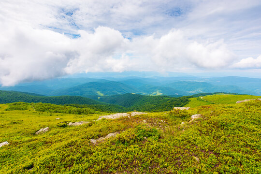 high Carpathian mountain summer landscape. meadow with huge stones among the grass on top of the hillside near the peak of mountain range. cloudy sky over alpine field