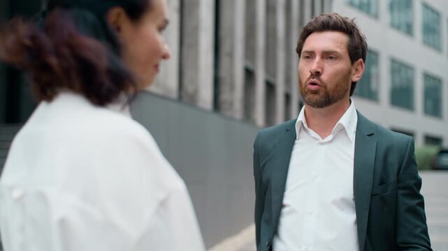 Caucasian business man irritated annoyed talking blaming intern woman in city. Two middle-aged managers problem in downtown. Businessman angry blame talk to businesswoman internship failure quarrel