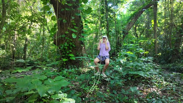 Woman climbing in slow motion with hands on lianas in a lush tropical cacao plantation, exploring nature and enjoying an active outdoor adventure in the Caribbean of Martinique island