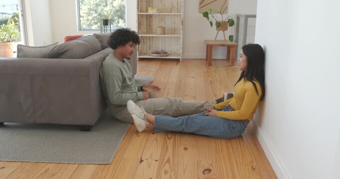 African American couple sitting on rug man talking gesturing as woman with book listening to learn