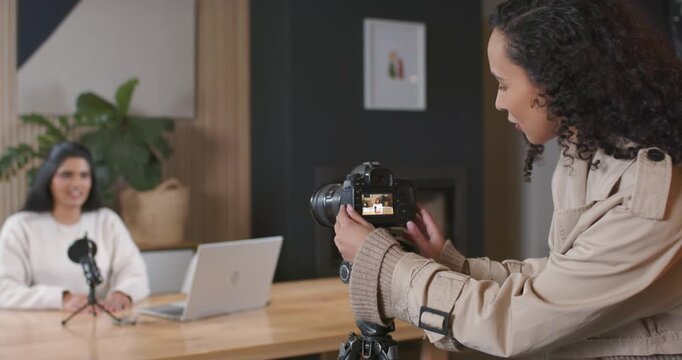Diverse female team checking monitor, adjusting DSLR while host rehearsing into mic for recording