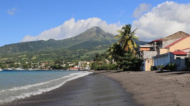 the French Antilles gorgeous coastline is exemplified by St Pierre Beach, which features black volcanic sand, crashing waves, sailboats on the Caribbean Sea, and Martinique's Mount Pelee volcano.