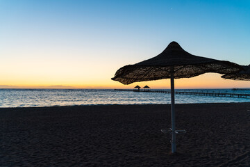 Thatched beach parasol beside the Red Sea at dawn © Dave Marzotto