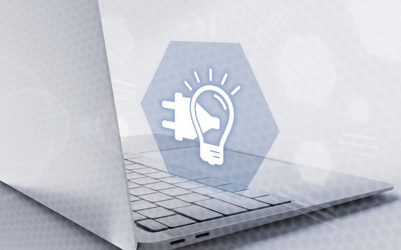 Imagen conceptual de una aplicaci&oacute;n inform&aacute;tica con un icono de bombilla y enchufe sobre un ordenador port&aacute;til moderno en un entorno tecnol&oacute;gico digital.