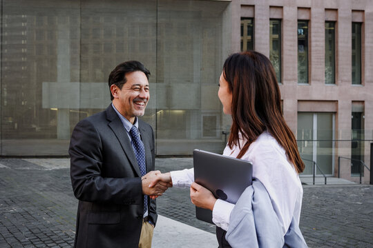 couple of Adult Hispanic Business Woman and man shaking hands Outdoors in winter at morning outdoors in street city
