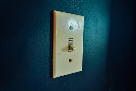 Old Toggle Light Switch in the Off Position on a Dark Blue Wall