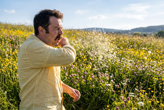Hay fever sneezing man in wildflower meadow outdoors