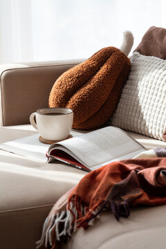 Cozy relaxation scene with book and coffee on sofa warm autumn blanket autumn pillow