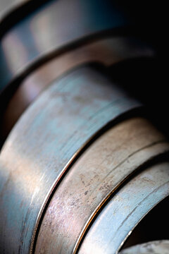 Closeup view of twisted flat steel strips and metal profiles, showing their surface texture, irregular contours and intersecting lines, torsional deformation and the structural characteristics of meta