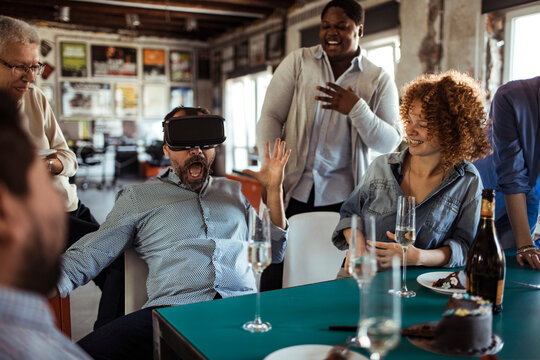 Coworkers laugh as man tries vr headset at office party