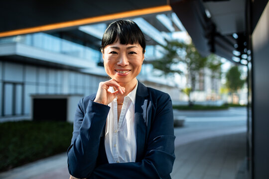 Confident businesswoman smiling with hand on chin outdoors