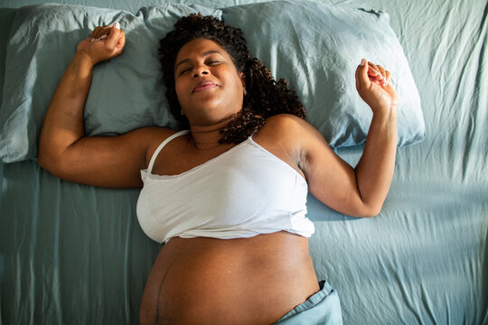 Pregnant woman relaxing in bed with eyes closed