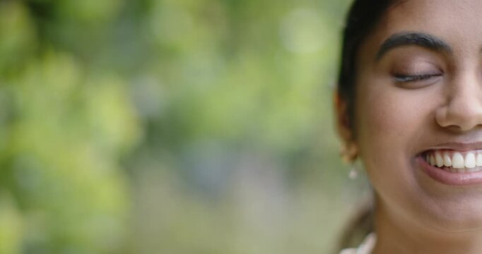 Adult Indian woman smiling while camera pulling back, revealing gold earrings and collar